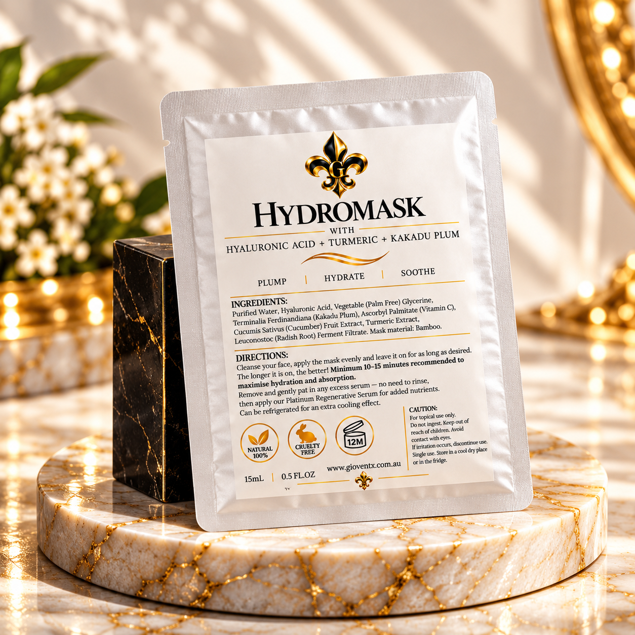 A single stand-up pouch of Hydromask facial mask powder is centered on a polished marble pedestal with a dark stone block behind it. The package is metallic silver with a large white front label and black/gold text.